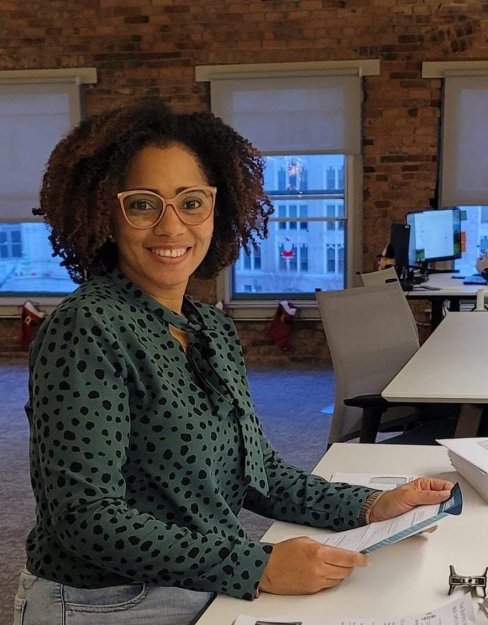 A woman smiles while she sorts mail at a desk