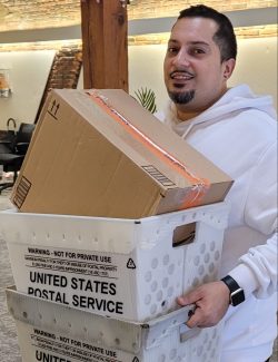 A man in a white sweatshirt holds boxes of mail in the Albany office of New York Registered Agent LLC.