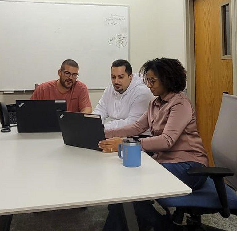 Two male and one female employee of New York Registered Agent LLC work on laptops in the Albany office.