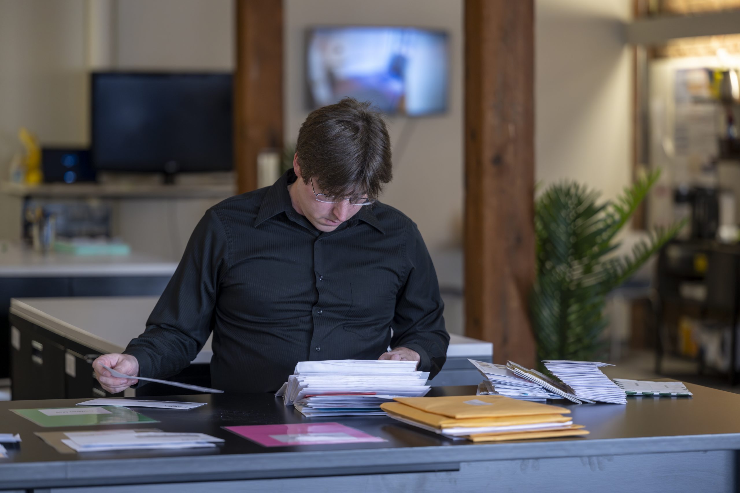 An employee of New York Registered Agent looks down at documents on a desk.