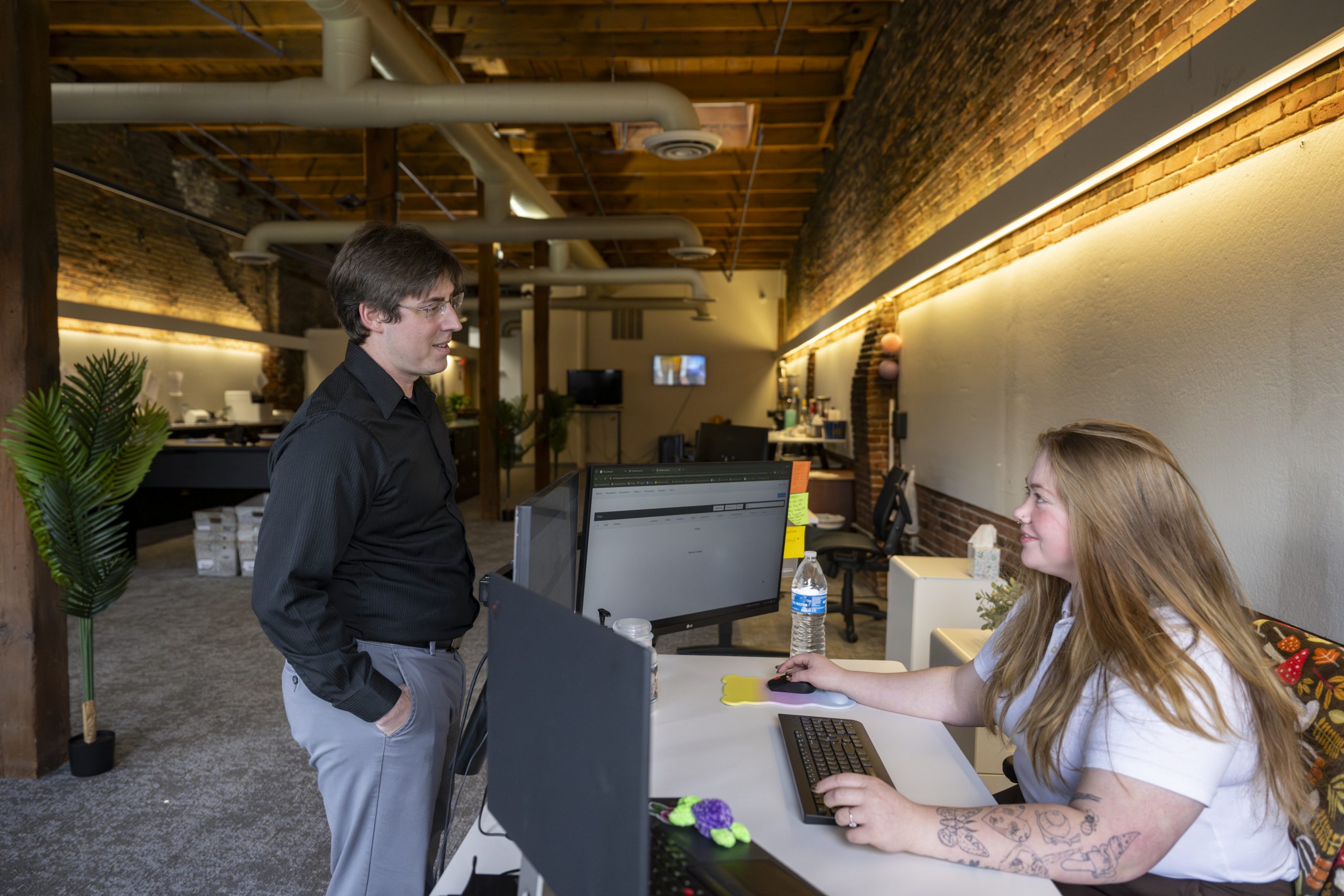 A standing man talks to a woman sitting at a desk inside the offices of New York Registered Agent.