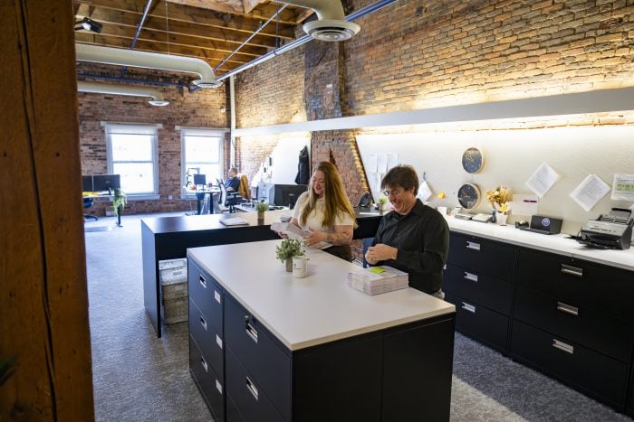 Two employees of New York Registered Agent review documents while standing at a table.